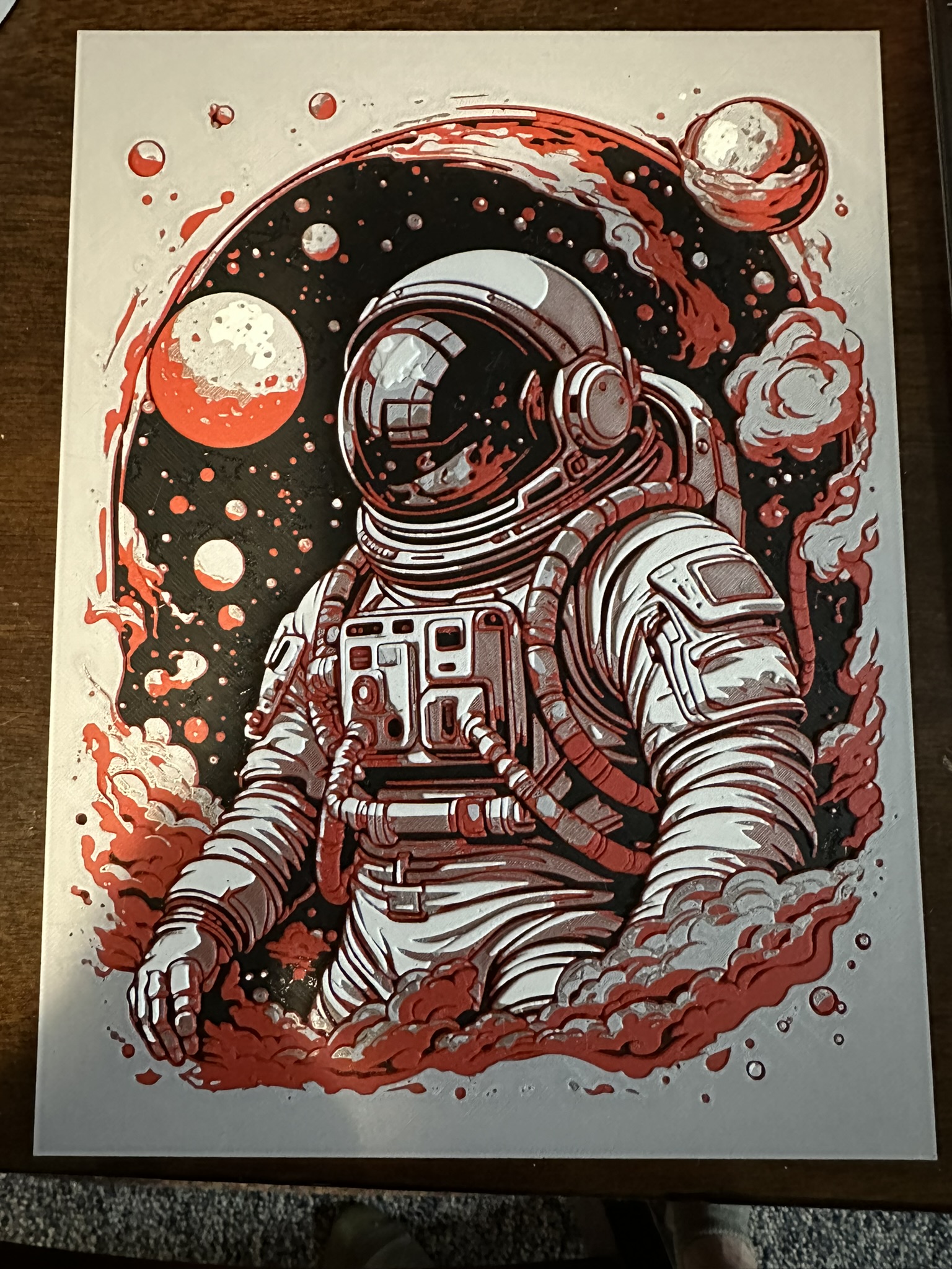 Red, white, and black astronaut relief with planets and swirling shapes