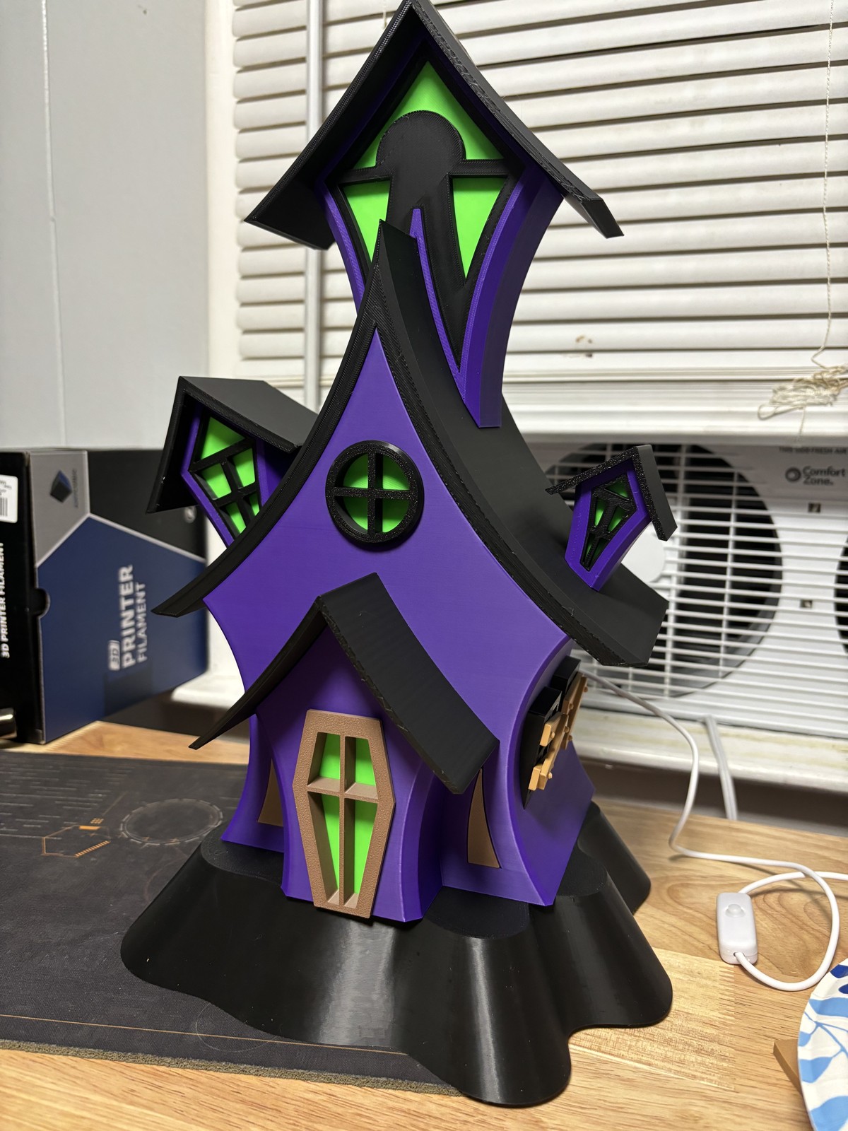 Purple and green crooked haunted-house model with the lights off