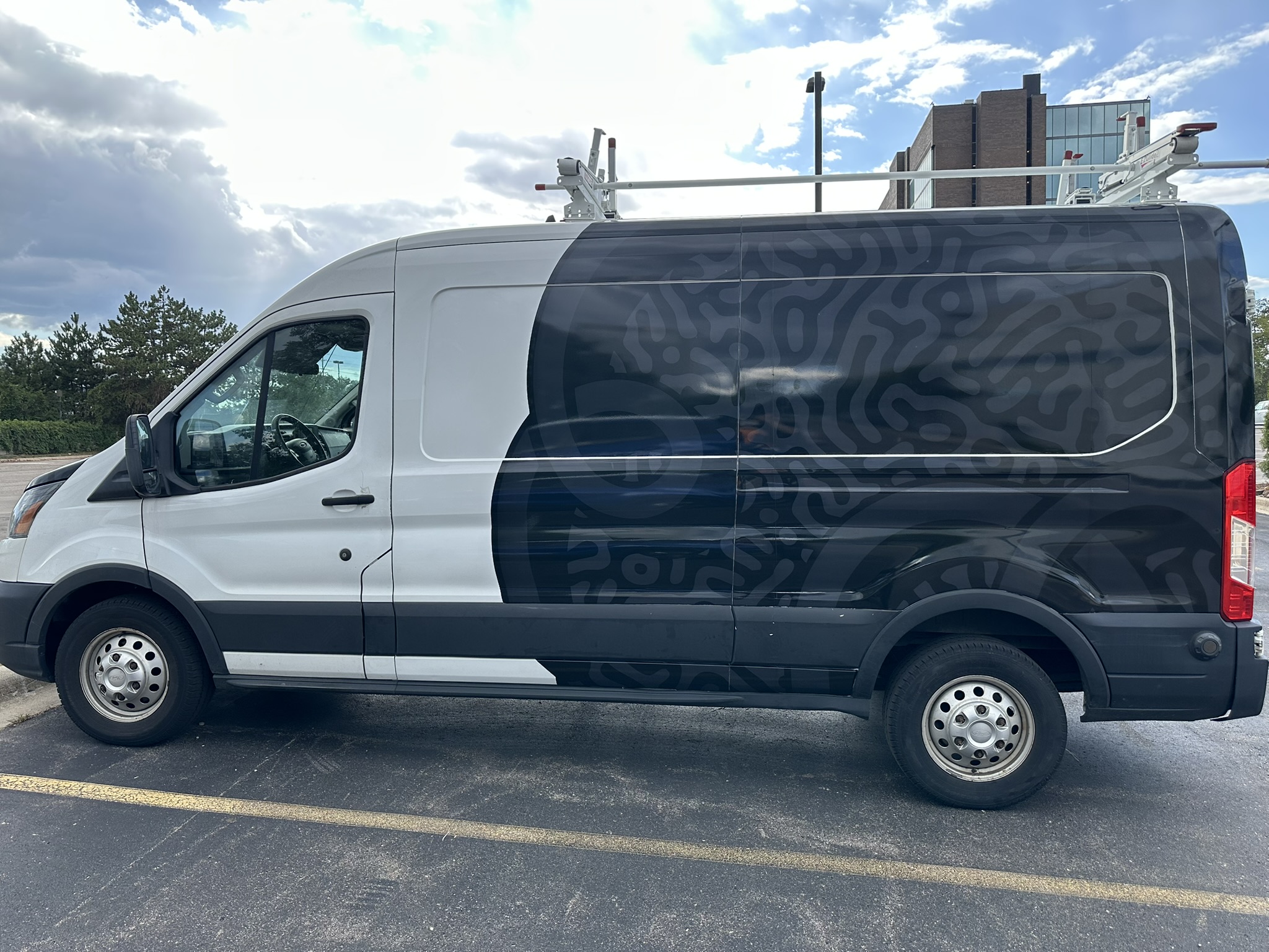 Dark patterned partial wrap on a white commercial van