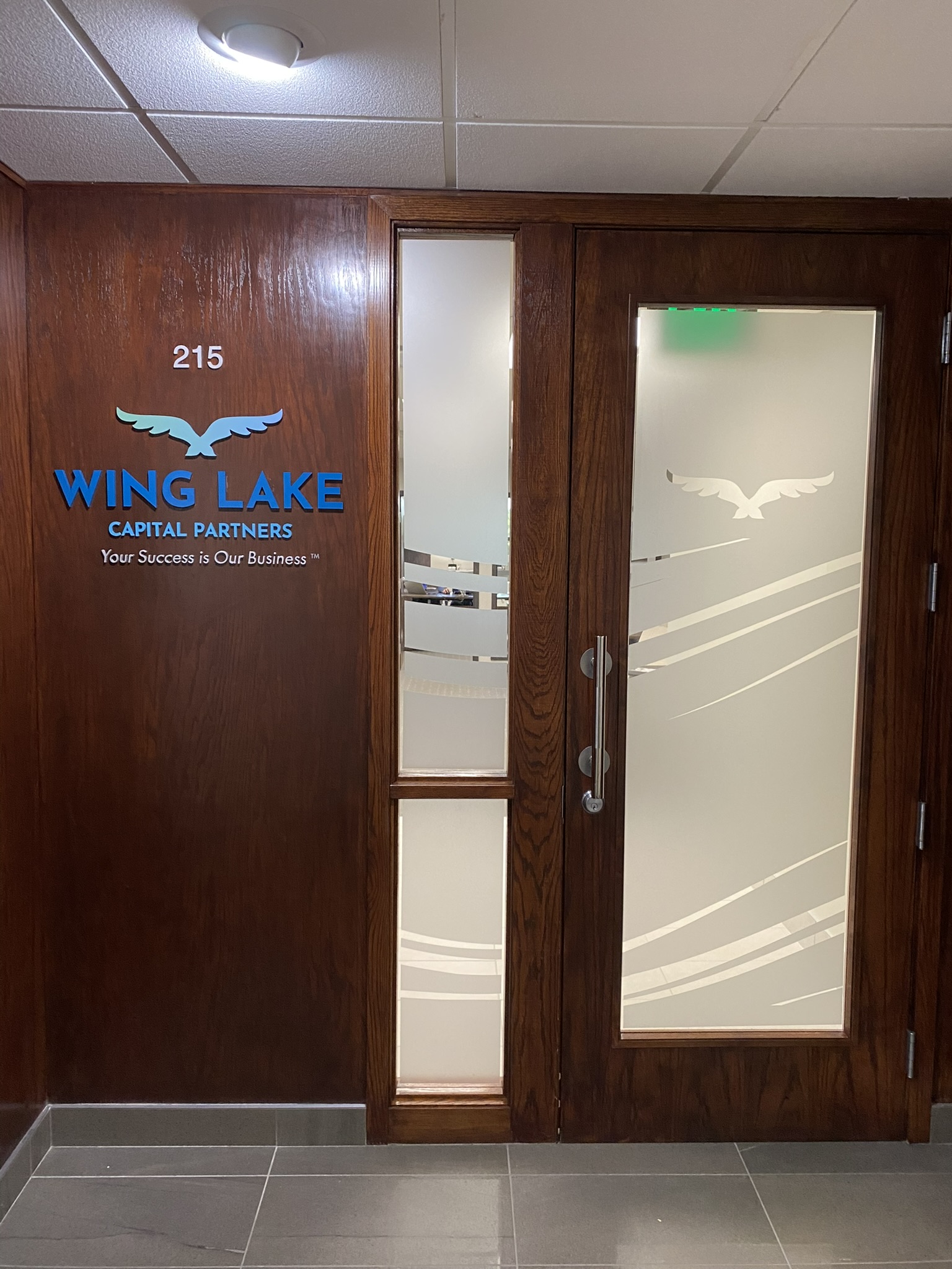 Wing Lake Capital Partners sign beside a door with frosted glass graphics